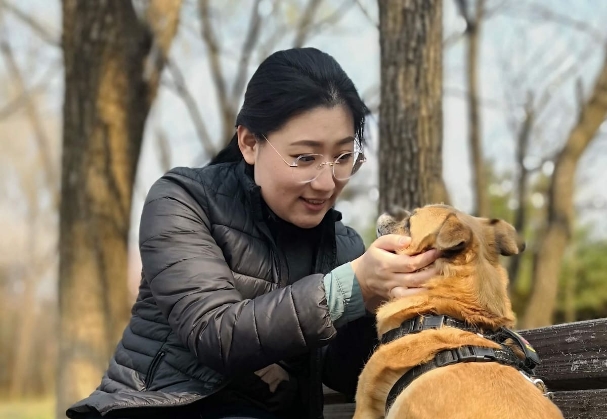 Pet owner petting dog on park bench - Zoetis