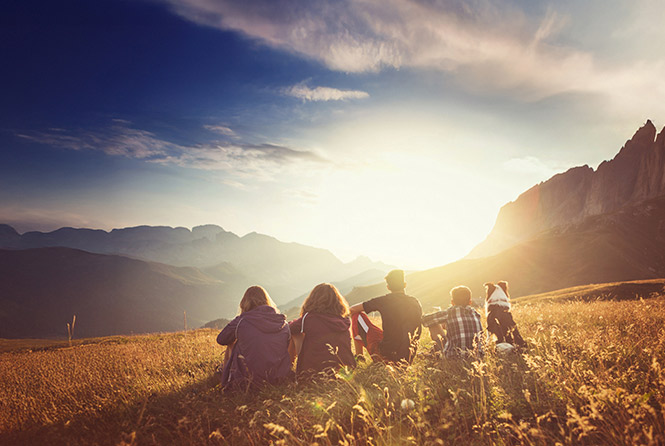 Group of people with dog viewing sunset from top of mountainous vista point- Zoetis